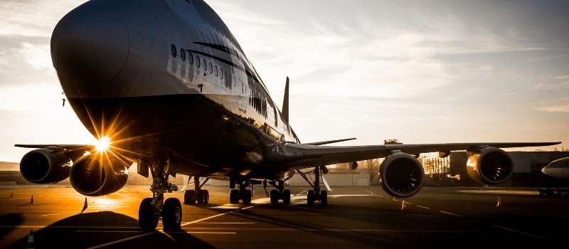 An airplane parked on a tarmac during sunrise.