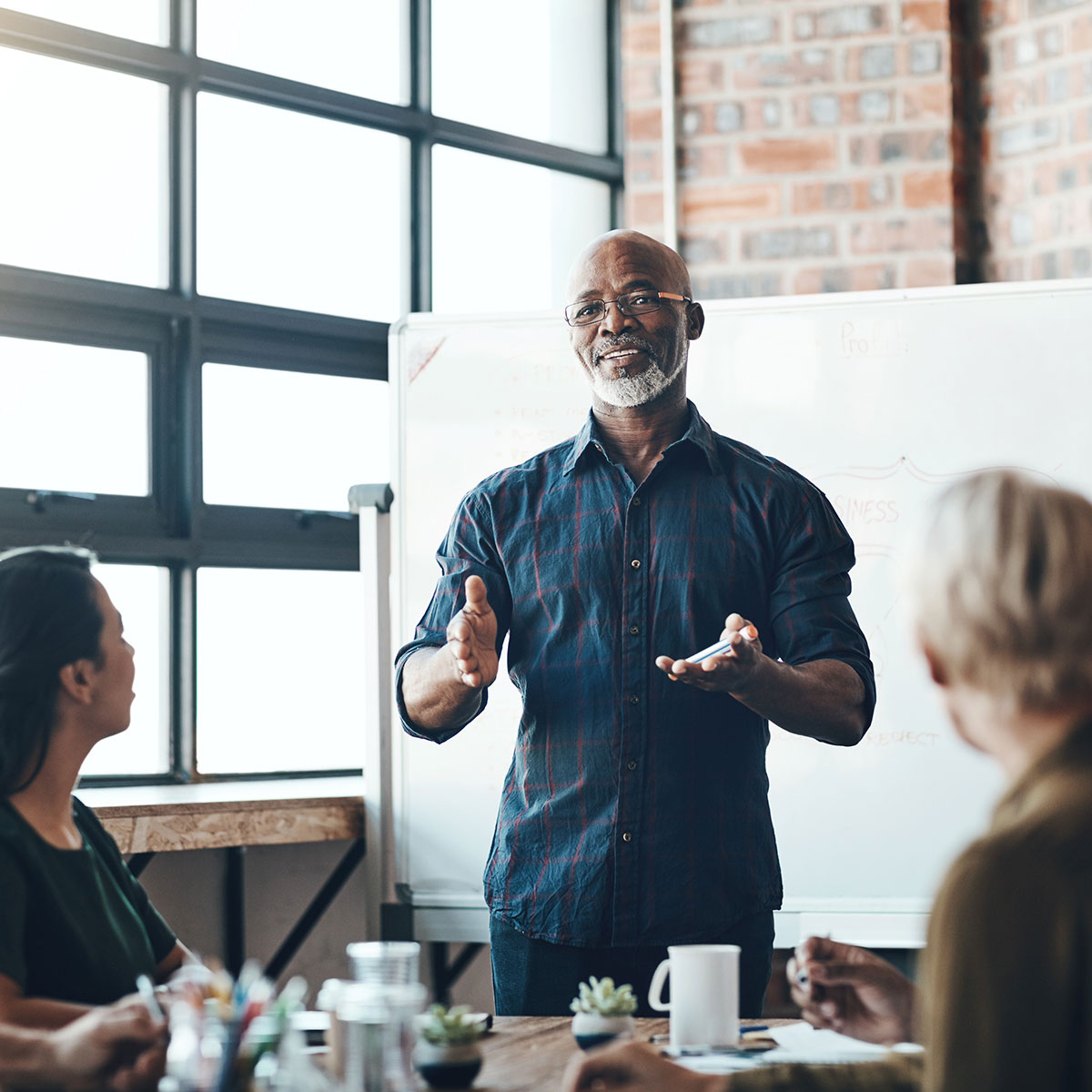 Senior business man doing presentation, planning and talking in a meeting, seminar or training workshop in a boardroom. Manager sharing ideas, teaching and coaching new employees during conference