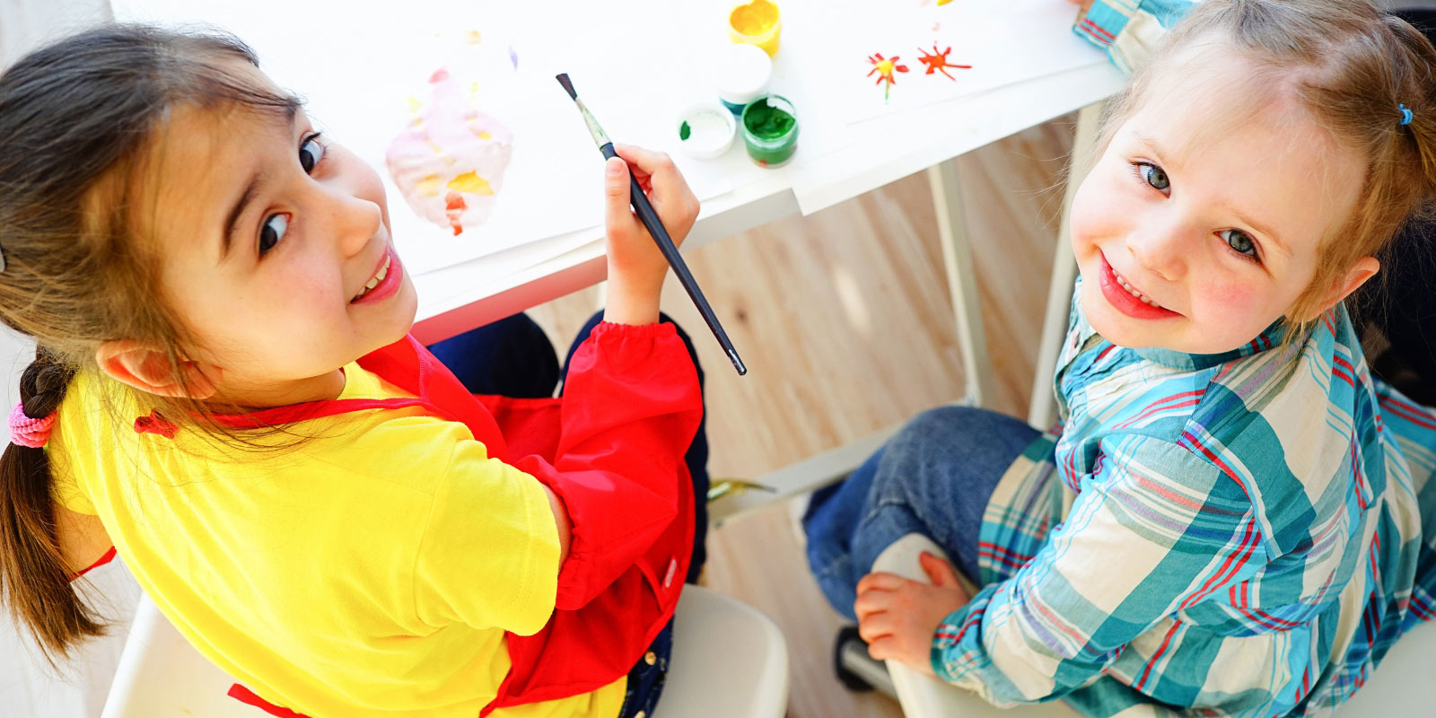 Two young girls painting pictures.