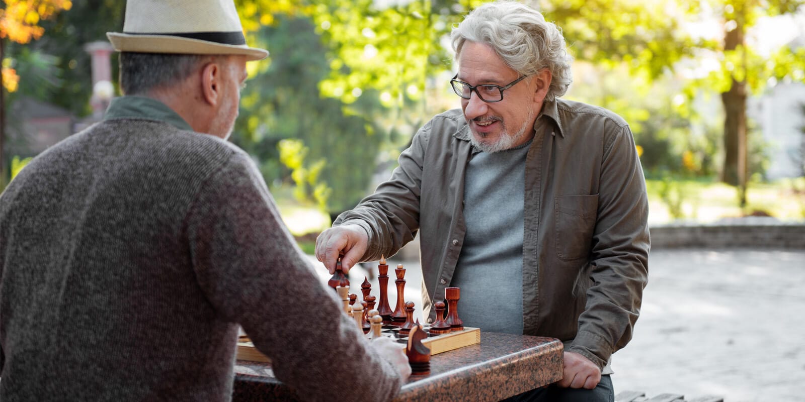 Cheerful senior men playing chess together outdoor