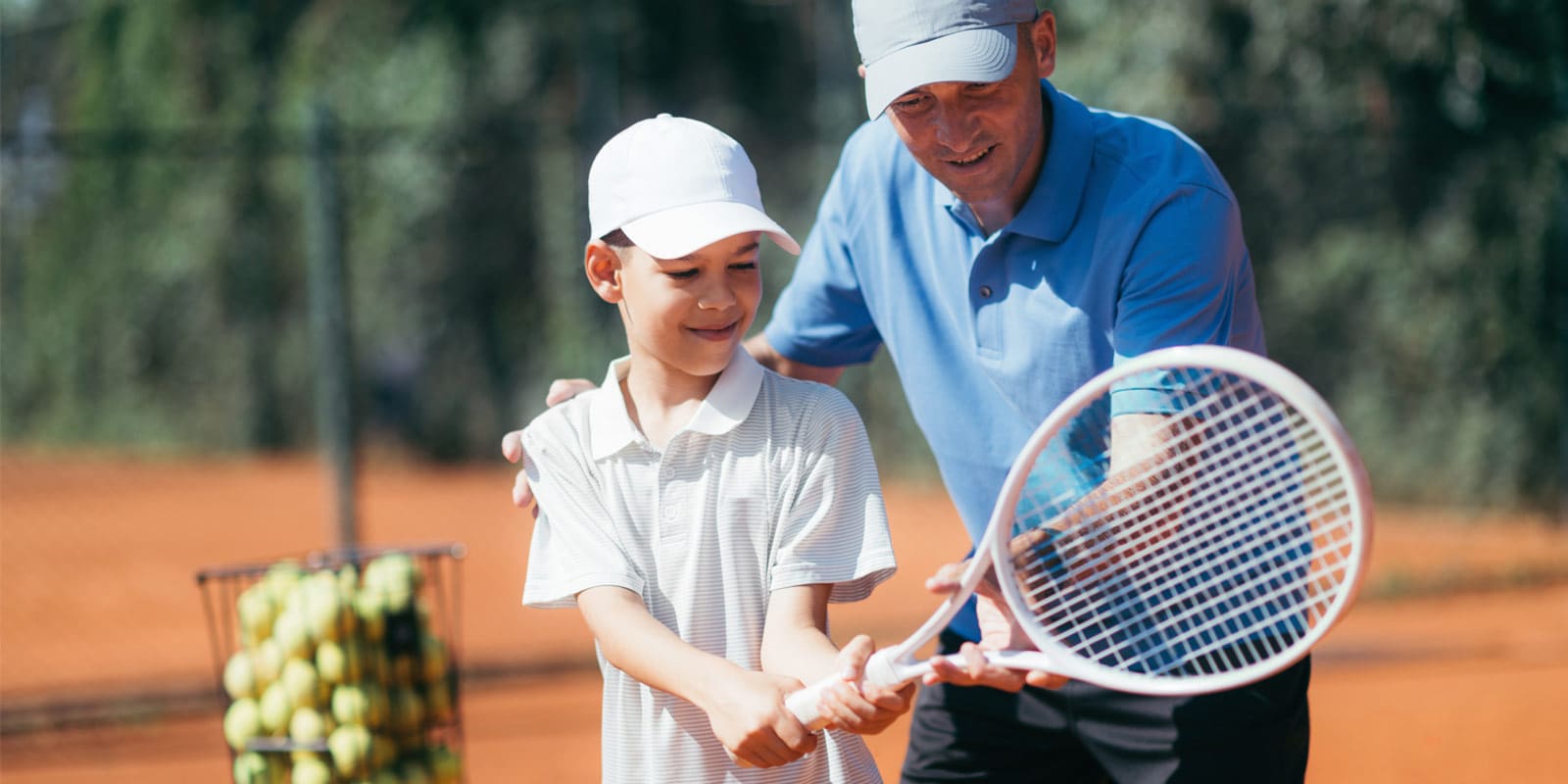 Adult coach teaching a child how to hold a tennis racket