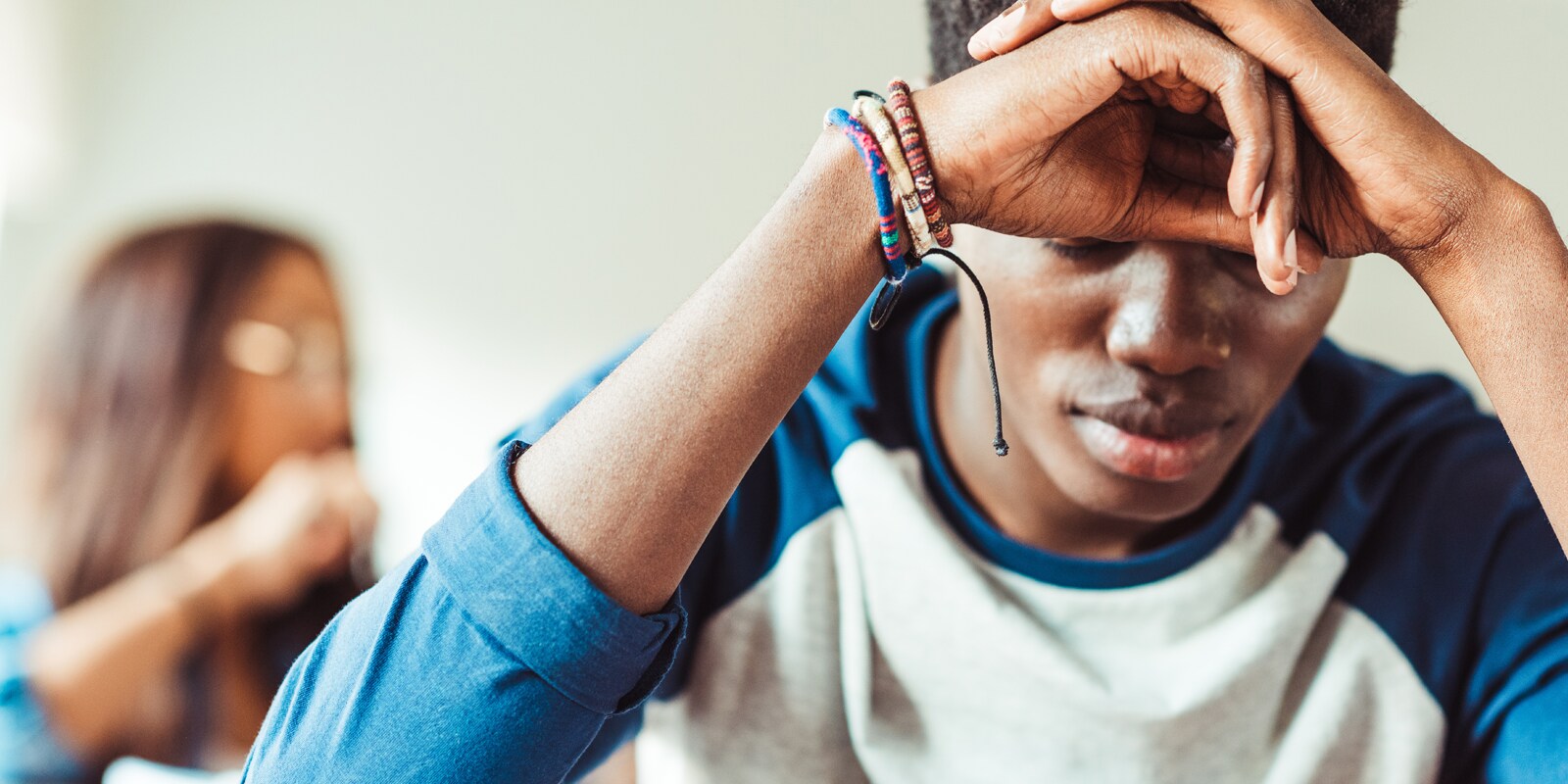 Youth looking down leaning head on hands
