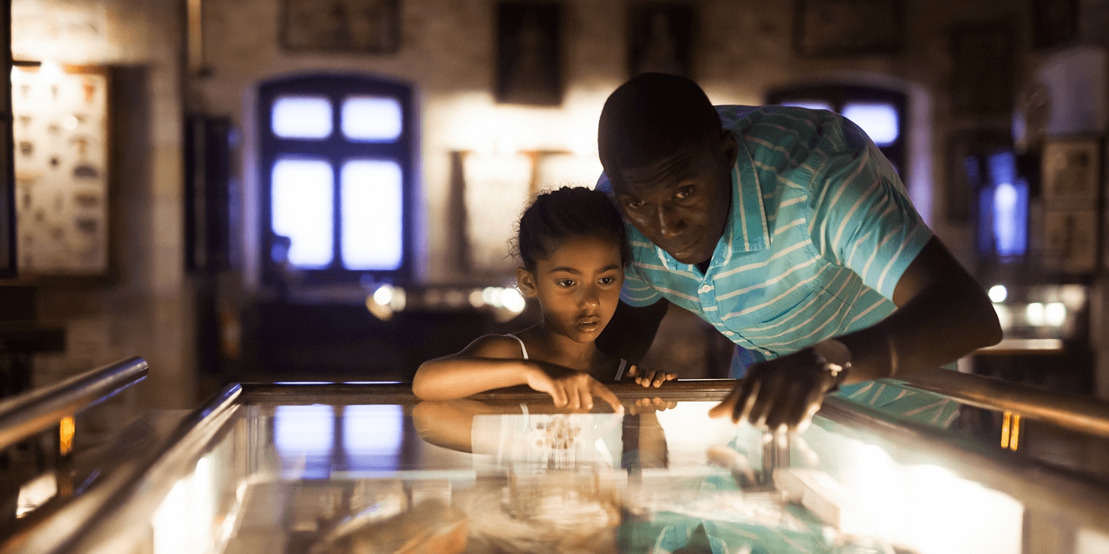 Child and adult looking into glass top display case
