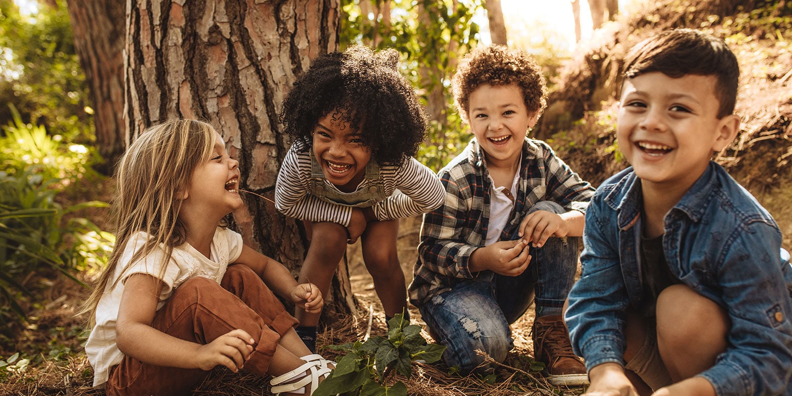 A group of children sitting outside under a tree. 